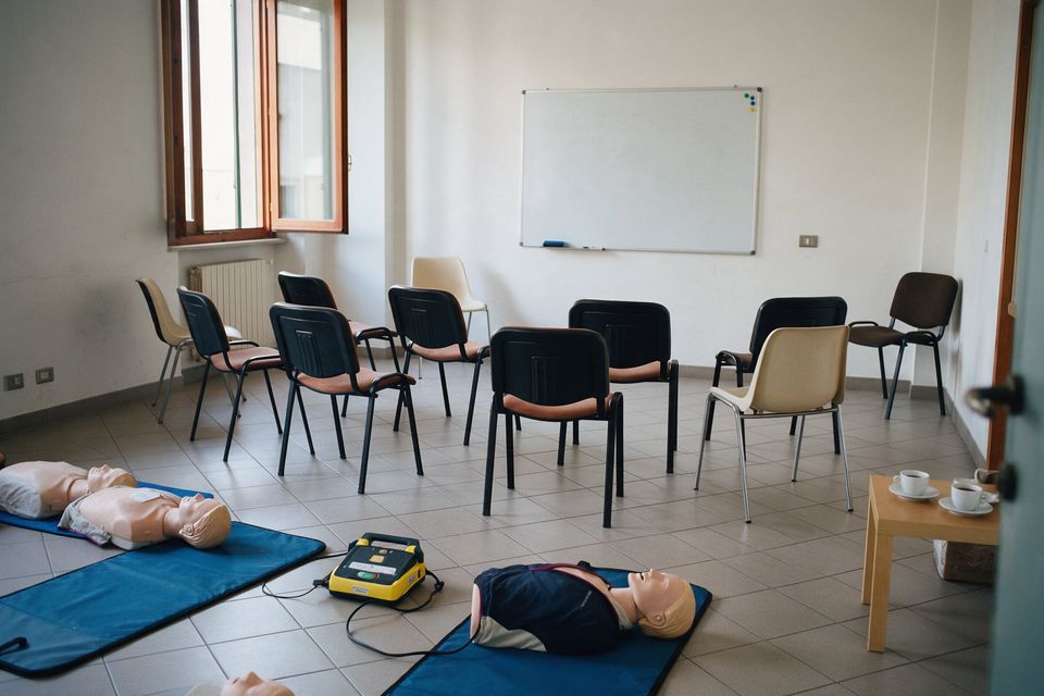 Aula di formazione con le sedie in cerchio, manichini per la rianimazione e un defibrillatore didattico a terra